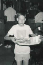 Young boy has a loaded tray of breakfast food served at the hot breakfast buffet.